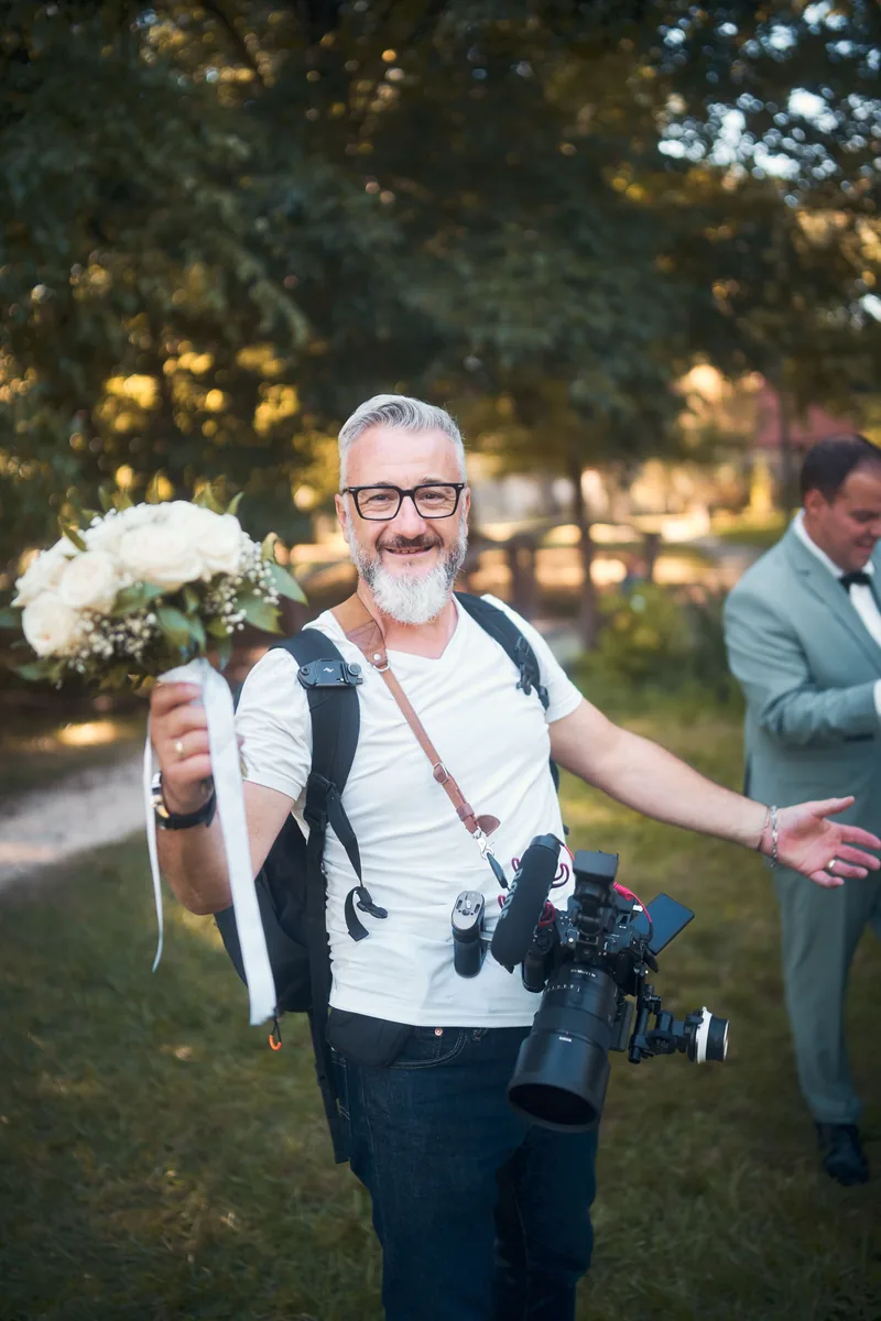 Laurent Dimberton en tournage, caméra à la main, tenant le bouquet de la mariée au mariage d'Amandine et Benjamin